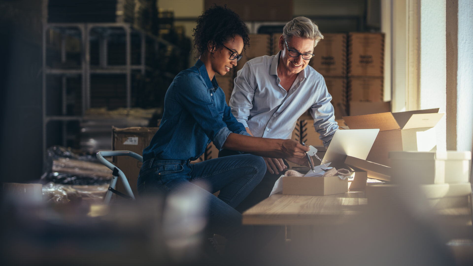Man woman at a sunny desk surrounded by boxes