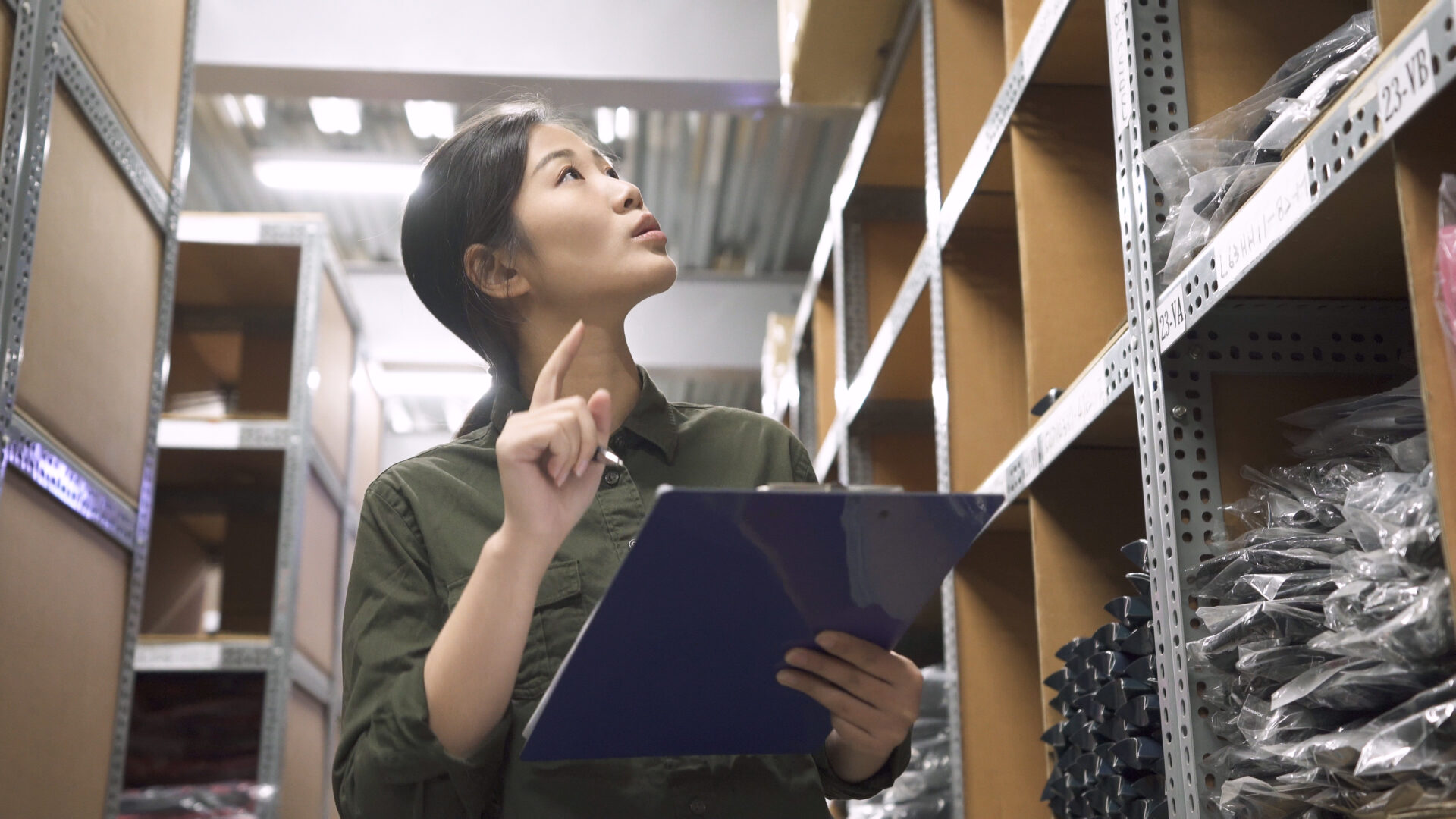 woman looking at shelves with  clip board and pen