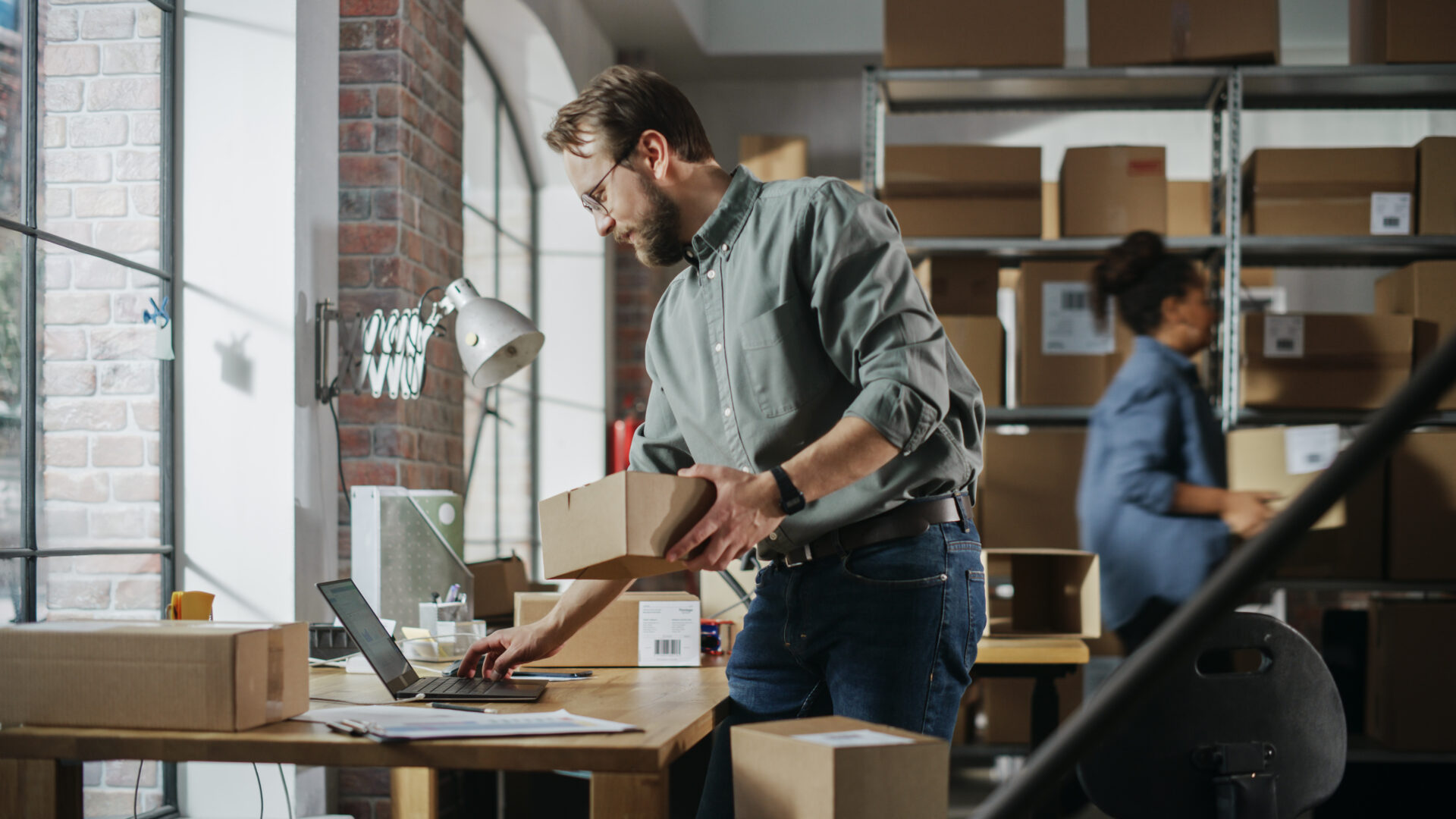 Man at am office desk with boxes on shelves