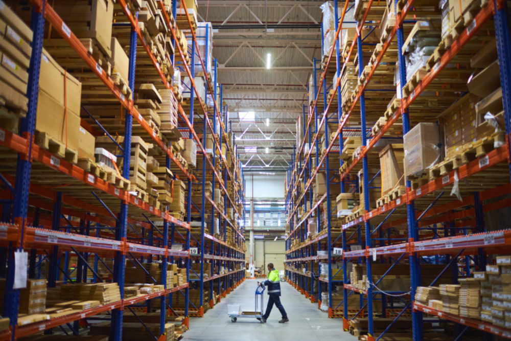 Warehouse employee pushing a cart with only one thing on it through a large aisle