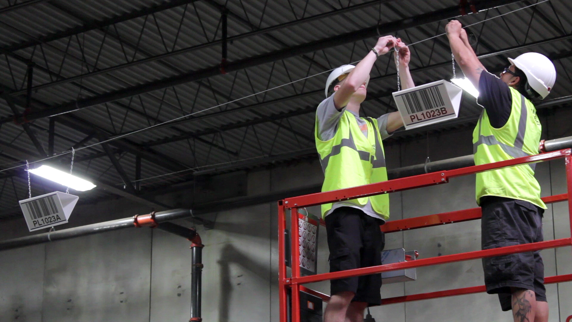 2 warehouse workers hanging signs